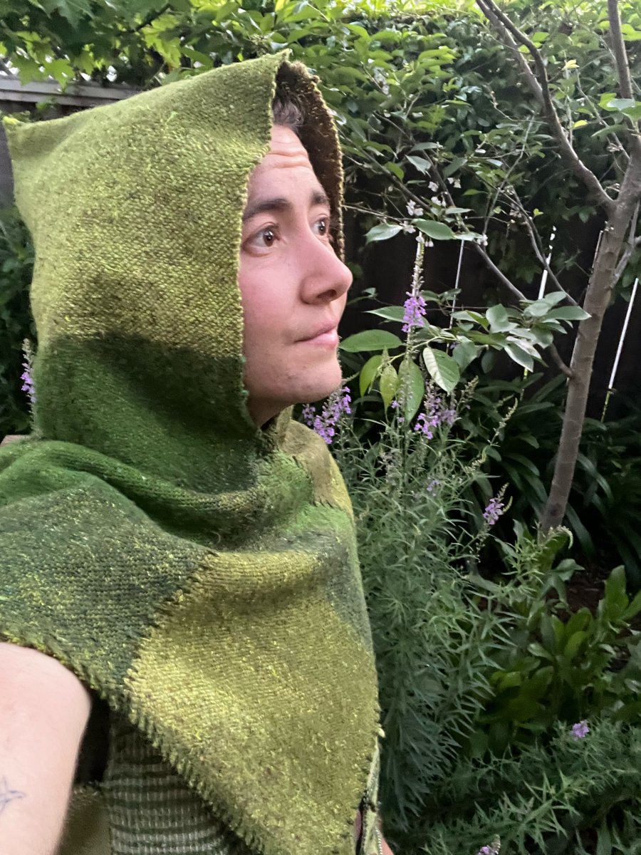 Photo of Soren in a green woven hood in a garden